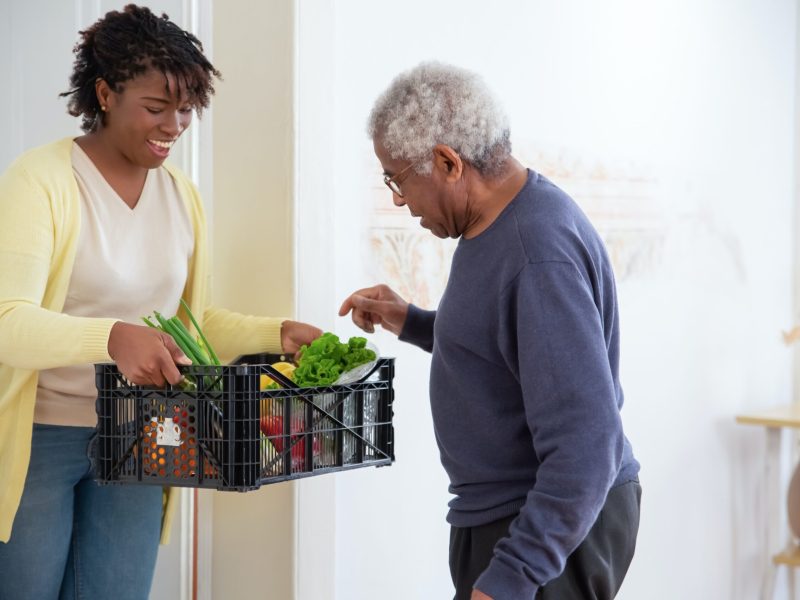Girl sharing a basket of groceries with elder man